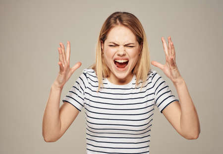 Fille en colère entrain de crier. La bouche est ouverte, les mains sont levées et les sourcils froncés.